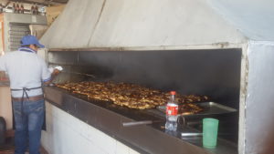 A 6 ft long grill covered with whole roast chickens
