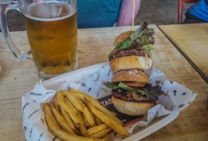 Two slider burgers on a skewer with an order of fries and a beer