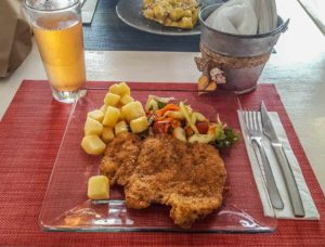 Breaded chicken filet with potatoes, vegetables and a glass of juice