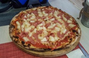 Ham and pineapple pizza on a wooden platter