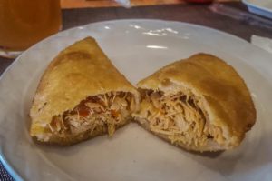A pulled chicken empanada cut in half with the inside showing