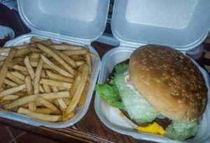 A burger and an order of fries, each in a styrofoam container