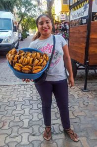 Mexican girl standing on Fifth Avenue with a big bowl of churros
