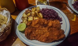 A huge schnitzel with a side of roasted potatoes and red cabbage