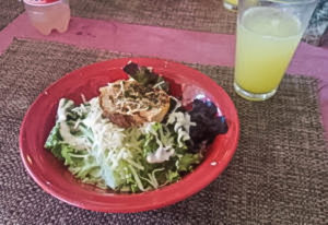 Caesar salad with Parmesan cheese in a red bowl with a lemonade