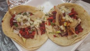 Two chorizo tacos on double flour tortillas, topped with cabbage and onions