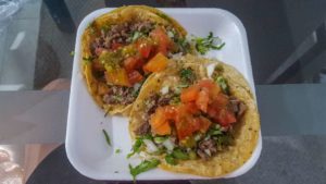 Beef tacos on corn tortillas with onions, cilantro and red salsa