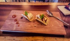 2 mini ice cream tacos on a wood platter with caramel garnish