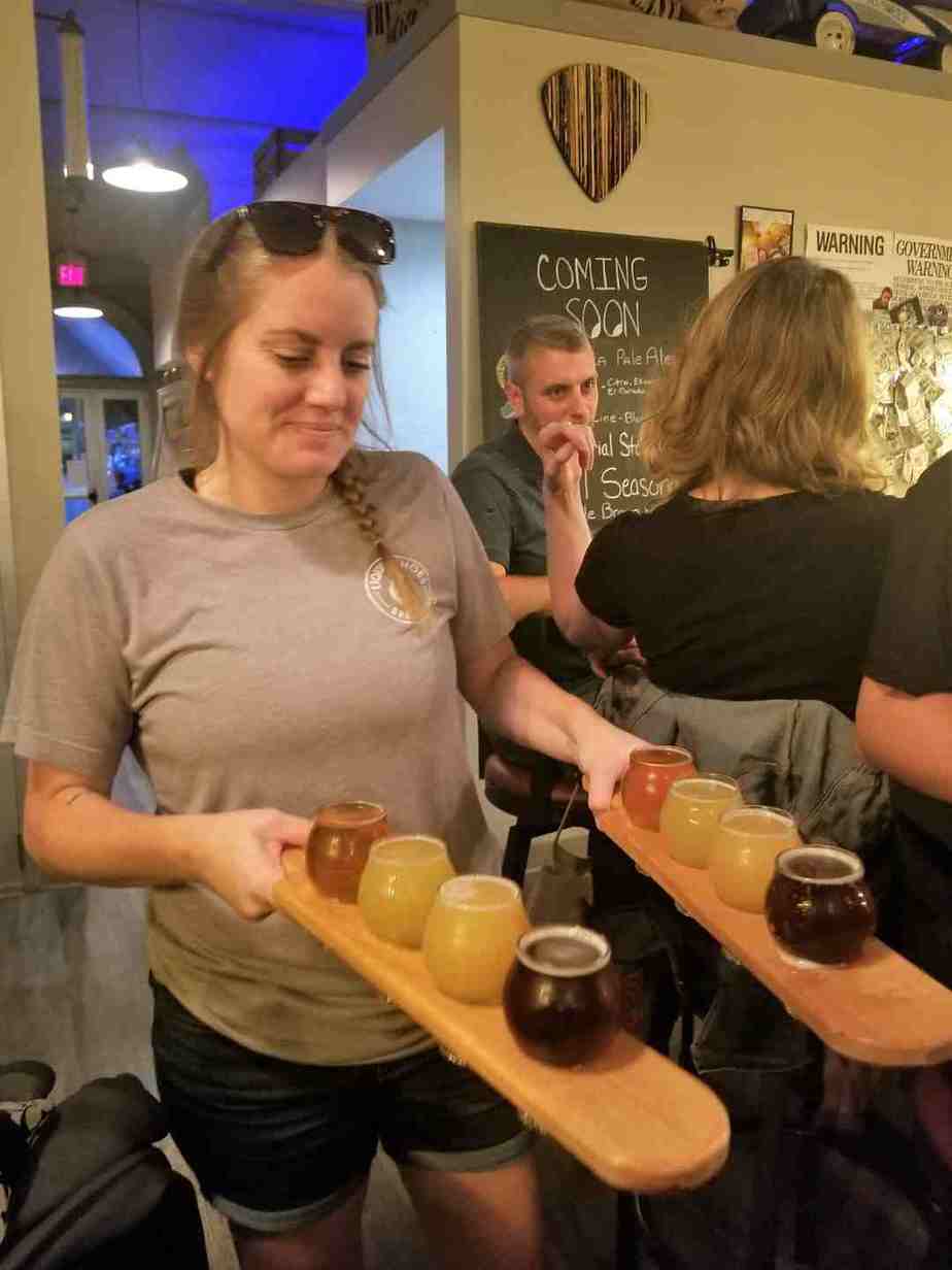 A local bartender carrying 2 flights of daught in Liquid Shoes Brewing on Market Street, Corning NY