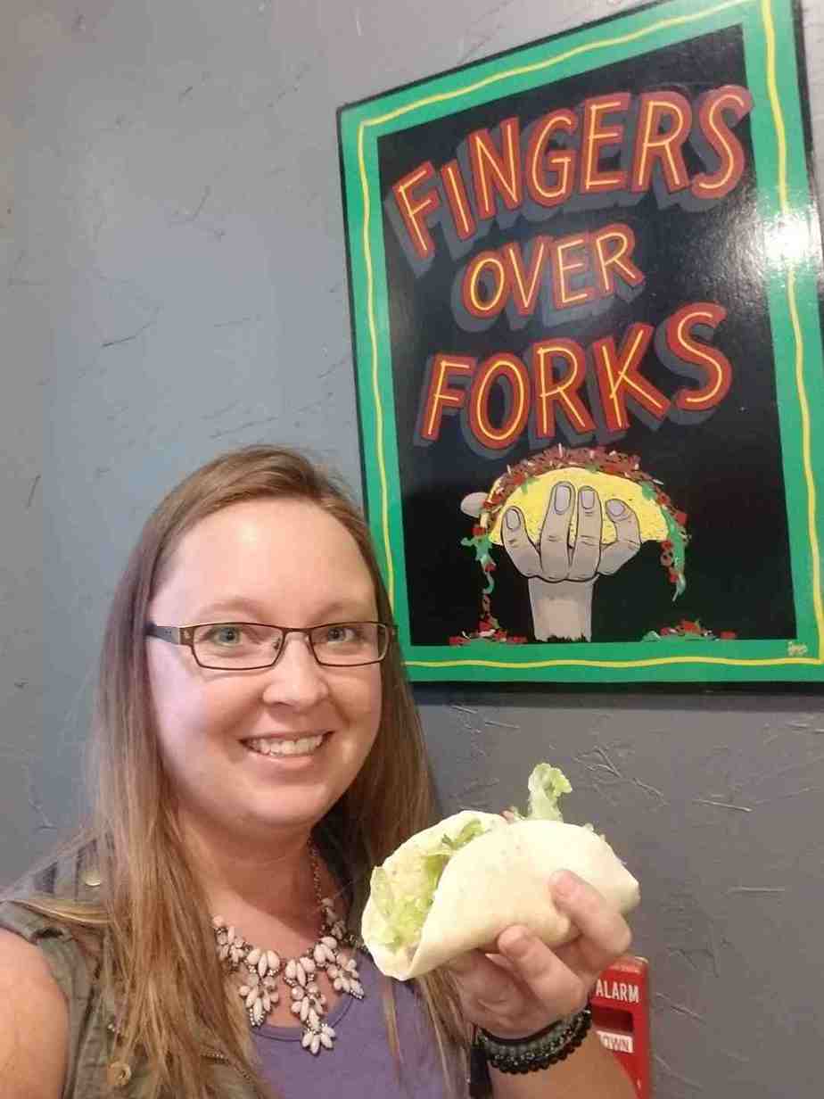 Me with my taco infront of the 'Fingers over Tacos' sign at Little Boomers