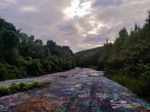 Image of graffiti highway on a cloudy day with sun peeking through the clouds