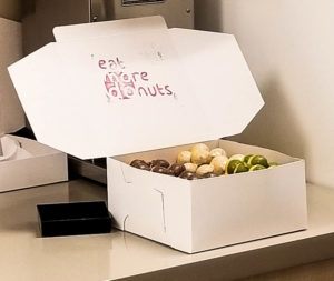 A box of Modo Donuts with 'Eat more donuts' on the lid