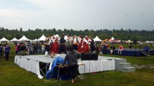 A group performing on stage with a row of food tents behind it