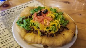 A plate sized Indian fry bread taco topped with taco beef, lettuce, cheese, tomatoes and olives at Custer's Trading Post and Cafe, Crow Agency, Montana