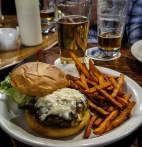 An open faced burger with pepper jack cheese and a side of sweet potato fries and a pint of beer at the Montana Bar in Miles City, Montana