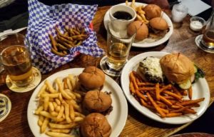 Overhead shot of beef sliders with fries, a cheeseburger with sweet potato fries, breaded asparagus and beers at Montana Bar in Miles City, Montana