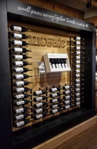A display of wine bottles arranged in a black square frame with the Mosaic name on the wall