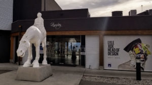 A white sculpture of a man sitting on a neighing horse in front of the front entrance of Liquidity Winery
