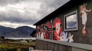 Ruby Blues Winery logo painted on a black wall, with Okanagan Lake in the background