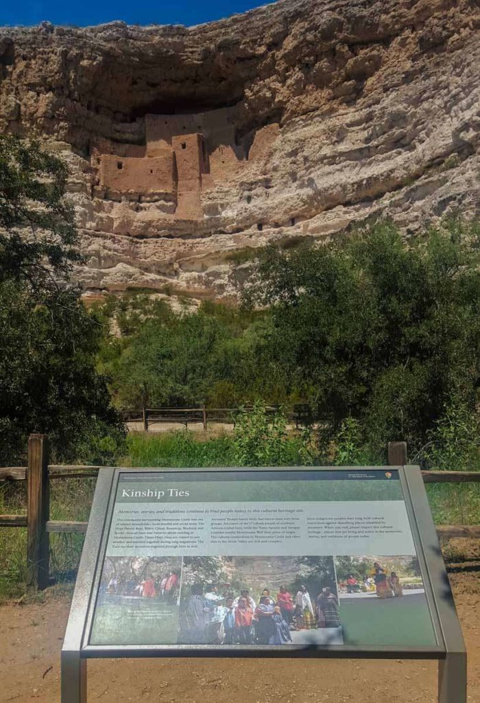 A plaque in front of a cliff that has a dwelling built into the side of it out of sandstone