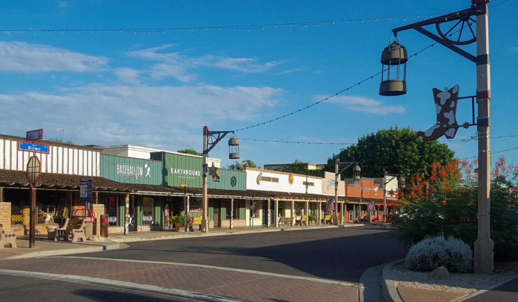 A line of shops along a street in Old Town Scottsdale with an antique streetlight and a big cowboy boot on the lamppost in the foreground
